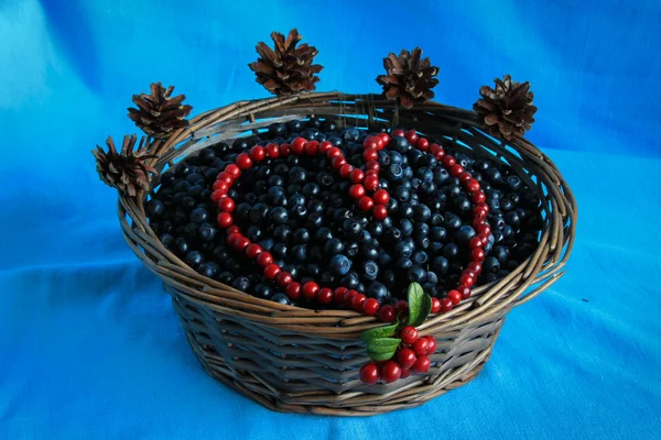 Delicious ripe blueberries in a wooden basket stands on a blue tablecloth — Stock Photo, Image