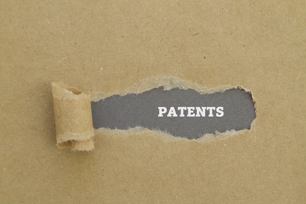 Patentes palabra escrita bajo papel roto . — Foto de Stock