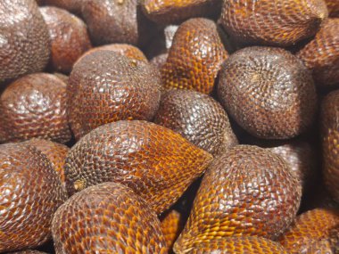 A detailed close-up of a pile of salak fruit, showcasing their unique scaly skin and brown hues, highlighting the texture and exotic nature of this tropical fruit.