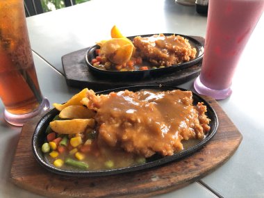 Siyah tabakta servis edilen tavuk bifteği restoranda servis ediliyor.