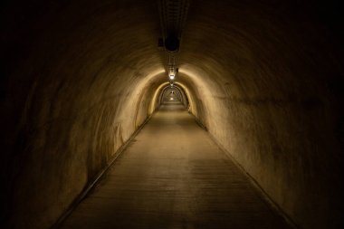 Zagreb, Croatia - August 23, 2024: Illuminated underground tunnel in Zagreb with arched concrete walls and a long perspective view leading toward distant figures.
