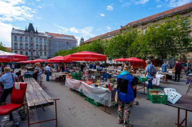 Zagreb, Hırvatistan - 23 Ağustos 2024: Zagreb 'deki güneşli sabah bit pazarı, kırmızı şemsiyeler altında tezgahlar, antika, giysi ve ilginç eşyalar satan satıcılar.