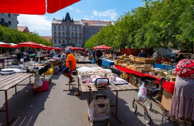 Zagreb, Hırvatistan - 23 Ağustos 2024: Zagreb 'deki güneşli sabah bit pazarı, kırmızı şemsiyeler altında tezgahlar, antika, giysi ve ilginç eşyalar satan satıcılar.