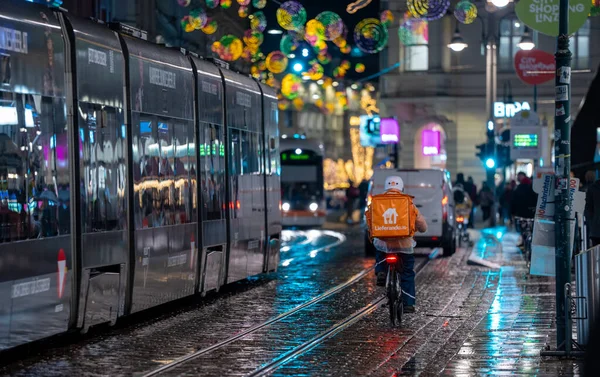 Linz, Avusturya - 20 Aralık 2024: Lieferando dağıtım bisikletçisi Noel akşamı yemek siparişi taşıyor