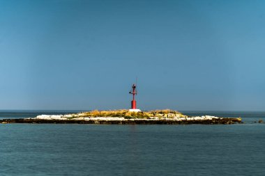 Porec, Hırvatistan - 13 Ağustos 2025: Sakin mavi sulardan, sakin dalgalar ve sakin deniz manzarasıyla çevrili, küçük, kayalık bir adacık yükseliyor.