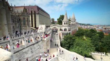 Budapeşte, Macaristan - 3 Mayıs 2025: Budapeşte 'deki Balıkçı Kalesi' nin güneşli manzarası, beyaz taş kuleler, turistlerle dolu merdivenler ve Macaristan 'da manzaralı bir şehir manzarası.