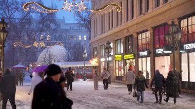 Budapeşte, Macaristan - 6 Ocak 2026: Canlı bir müşteri ve yayalar Budapeşte 'de kar kaplı bir moda caddesinde yürüyorlar alacakaranlıkta, ışıl ışıl parlayan mağazaların önünden geçerek.