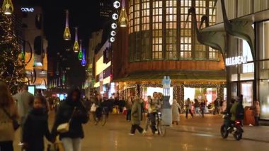 Lahey, Hollanda - 19 Aralık 2025: Lahey 'de hareketli bir gece sahnesi aydınlanmış sokaklar, tatil alışverişçileri, büyük bir Noel ağacı ve ayırt edici modern asılı fenerlerin yer aldığı.