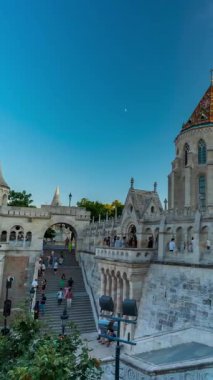 Budapeşte, Macaristan - 14 Haziran 2024: Balıkçı kalesi. Etrafta dolaşıp fotoğraf çeken büyük bir turist topluluğu. Zaman atlaması, kayma geçiş, dikey yönelim. Güneşli bir gün, açık bir gökyüzü.