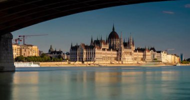 Budapeşte, Macaristan - 06 Ağustos 2024: Altın saat boyunca parlamento binası. Margaret Köprüsü 'nün altından görüntü. Zaman atlaması. Güneşli bir gün, açık bir gökyüzü.