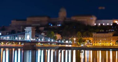 Budapeşte, Macaristan - 10 Ağustos 2024: Buda Şatosu ve Zincir Köprüsü, gece. Sztehlo Gabor caddesine odaklanmış. Zaman aşımı, yakınlaştırma geçişi.