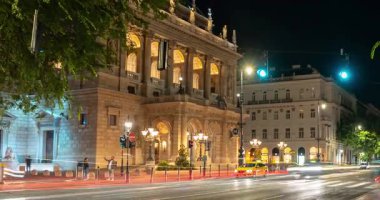 Budapeşte, Macaristan - 10 Ağustos 2024: Budapeşte 'nin opera binası yakınlarında gece araba trafiği. Zaman aşımı, yakınlaştırma geçişi.