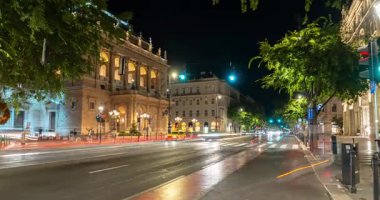 Budapeşte, Macaristan - 10 Ağustos 2024: Budapeşte 'nin opera binası yakınlarında gece araba trafiği. Zaman atlamalı, yakınlaştırmalı geçiş.