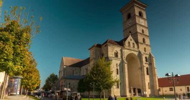 Alba Iulia, Romanya - 20 Ekim 2024: Str. Mihai Viteazul sokak manzarası. Sağdaki Aziz Michael Katedrali. Zaman ayarlı, dönüşümü yakınlaştır. Açık gökyüzü güneşli gün.