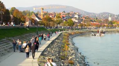 Szentendre, Macaristan - 27 Ekim 2024: Szentendre 'deki iyi korunan nehir kenarı boyunca yürüyen insanlar. Geçişi büyüt.