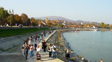 Szentendre, Macaristan - 27 Ekim 2024: Szentendre 'deki iyi korunan nehir kenarı boyunca yürüyen insanlar. Dönüşüme yakınlaş.