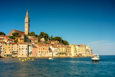 Rovinj, Hırvatistan - 15 Ağustos 2025: Rovinj 'in renkli sahil evleri ve St. Euphemia kulesinin hareketin bulanık turkuaz deniz manzarasına göz yumduğu tarihi ufuk çizgisini canlı uzun pozlu bir çekim yakaladı.