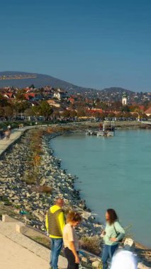 Szentendre, Macaristan - 27 Ekim 2024: Riverside Stroll: The Charming Embankment of Szentendre. Zaman geçişi, kaydırma geçişi, dikey yönelim.
