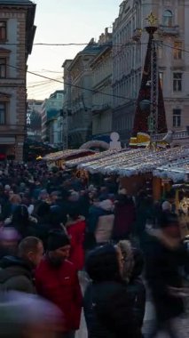 Budapeşte, Macaristan - 23 Kasım 2024: St Stephens Bazilikası 'nda Noel Pazarı. Kilisenin büyük kubbesinin altında sıcak şarap tezgahları ve el yapımı hediyeler parlıyor. Zaman ayarlı, yakınlaştır geçişi, dikey.