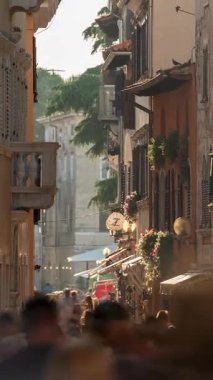 Porec, Hırvatistan - 13 Ağustos 2025: Zaman aşımı, geçişi yakınlaştırma, dikey. Hırvatistan 'da güneşli bir yaz akşamı, Porec' in eski kentinde kalabalık dar kaldırımlı caddeleri Istria 'da yüksek mevsimin telaş ve koşuşturmasını yakaladı.,...