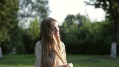 Güzel genç kadın Şehir Parkı içinde bir cep telefonu üzerinde söz.