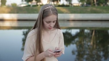 Nehir kıyısındaki oturan gülümseyen genç kız.