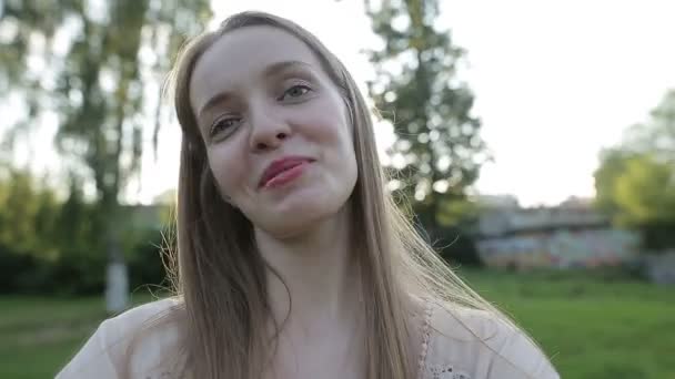 Retrato de una mujer sonriente haciendo foto de selfie en el parque — Vídeos de Stock