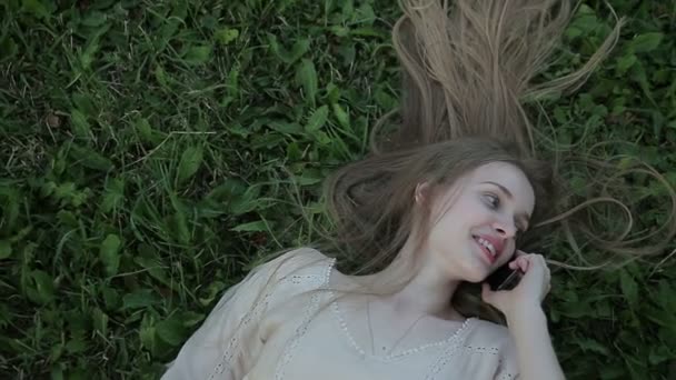 Portrait de belle femme couchée sur l'herbe verte avec téléphone — Video