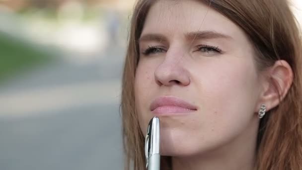 Bella giovane donna maniglie della penna faccia, sullo sfondo del parco verde estivo . — Video Stock
