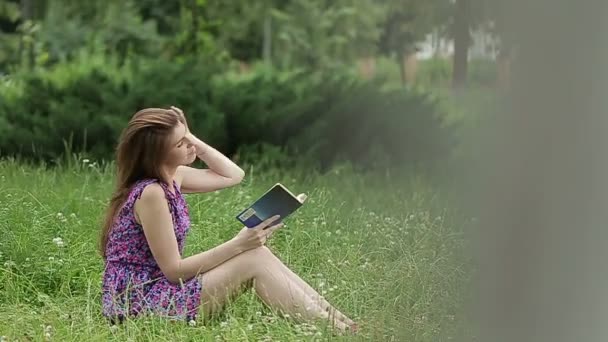 Junge schöne Frau liest ein Buch in der Natur — Stockvideo