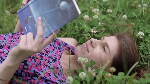 Adolescente estudiando tumbado en la hierba al aire libre. Estudiante leyendo libro . — Vídeos de Stock