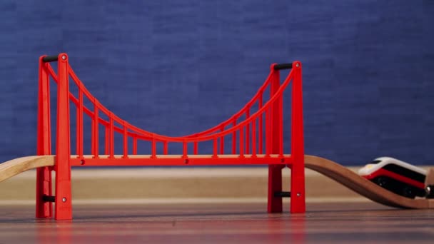 Tren de juguete subiendo por un puente rojo. Juguete ferrocarril de madera. — Vídeo de stock