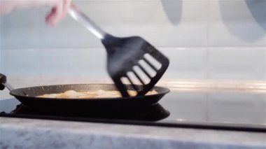 Bir kadın eli geleneksel Rus leziz kreplerini endüksiyon moderninde pişirir.