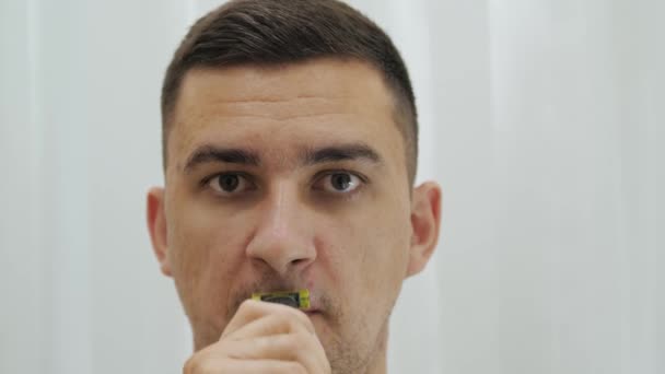 Detailní záběr pohledný muž je holení vousy a knír pomocí elektrické holicí strojek. — Stock video