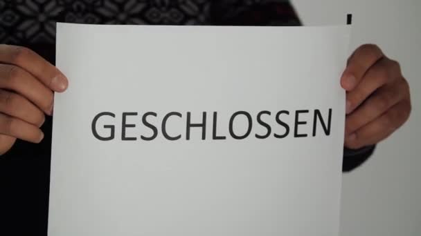 従業員が入口に案内看板「 Geschlossen 」を掛けます. — ストック動画
