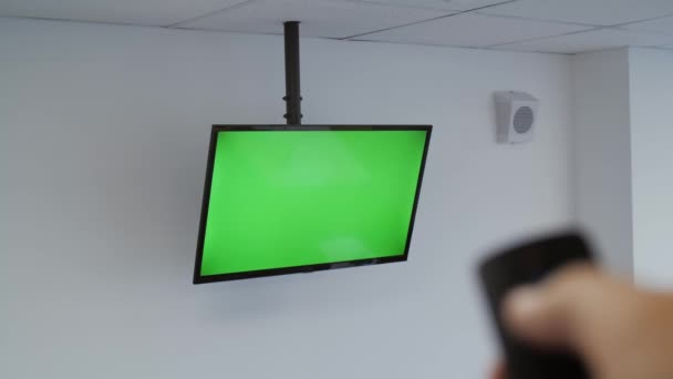 Ένα αρσενικό χέρι αλλάζει κανάλια σε μια τηλεόραση με μια πράσινη οθόνη — Αρχείο Βίντεο