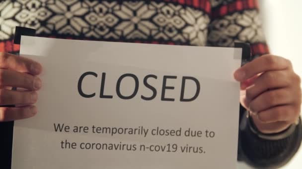 Закрыть бизнес владелец ставит закрытый знак на стеклянной двери из-за коронавируса. — стоковое видео