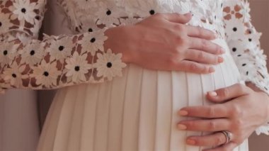 Genç hamile anne bebeğini karnında tutuyor. Doğum bakımı ve kadın hamileliği kavramı.