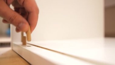 Ahşap pimi delinmiş deliğe sokuyorum. Yeni beyaz dolap monte ediliyor.