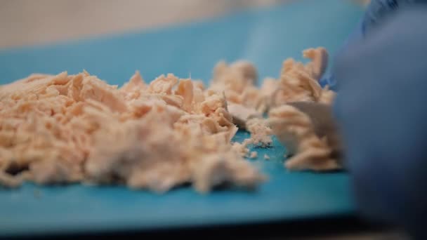 Chef cuts boiled chicken fillet on a blue plastic board — Stock Video