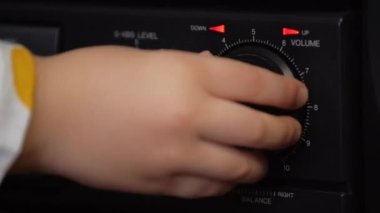 Bir çocuk klasik bir teyp üzerindeki ses kontrolünü çevirir..