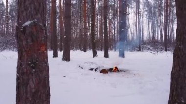 Kış ormanında kamp ateşinin üzerinde bir dron uçurmak.