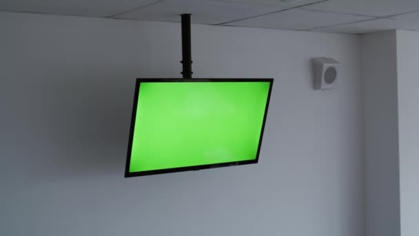 Primer plano gran televisor de pantalla verde en una sala de conferencias blanca y bien iluminada sin nadie en ella — Vídeos de Stock