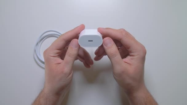 Cargador de poder blanco en manos de hombres. Adaptador de corriente USB-C de 20W de Apple. — Vídeo de stock