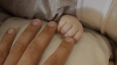 Baba yeni doğmuş bebeğinin elini tutuyor ve dokunuyor..