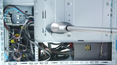 Erkek el, içerideki masaüstü bilgisayarını veya sunucuyu temizlemek için fırçayla elektrikli süpürge borusunu tutuyor.