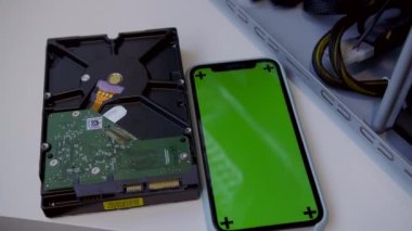 Modern bir akıllı telefonun yanındaki beyaz bir masada yeni bir sabit disk. Kripto para birimi madenciliği kavramı.