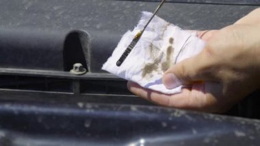 Oto tamircisi motordan yağ çubuğunu çıkarıp beyaz bir bezle siler..