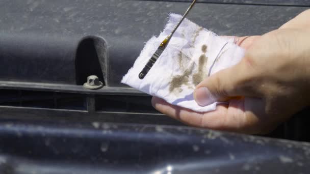 Autó szerelő eltávolítja az olaj dipstick a motorról, és törli azt egy fehér ruhával. — Stock videók