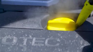 Buhar temizleyicisiyle kapağı temizliyorum.